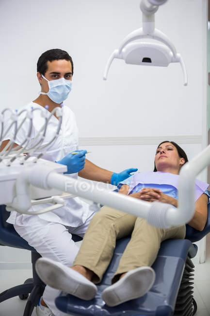 Odontóloga retratista atendiendo paciente femenina en la clínica - foto de stock