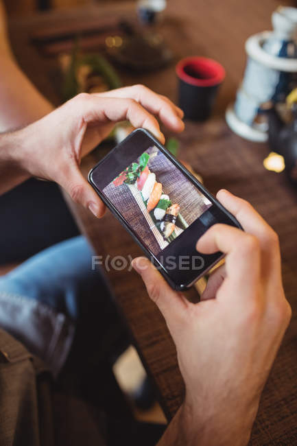 Man taking photo of sushi in restaurant — Stock Photo