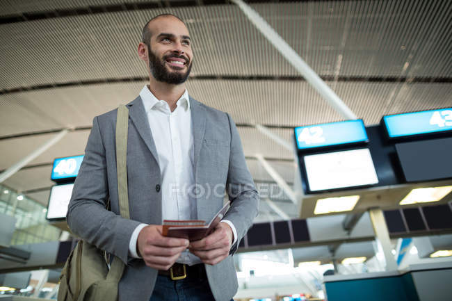 Empresário sorridente segurando um cartão de embarque e passaporte no terminal do aeroporto — Fotografia de Stock