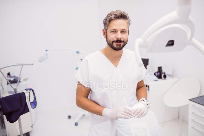 Retrato de un dentista masculino seguro de sí mismo de pie en la clínica - foto de stock