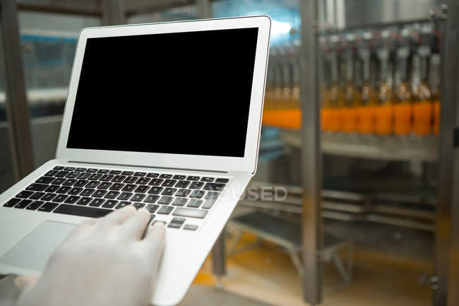 Mano ritagliata del lavoratore che utilizza il computer portatile nella fabbrica di succhi — Foto stock