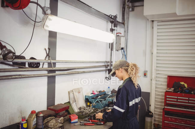 Mécanicien féminin organiser des outils dans le garage de réparation — Photo de stock