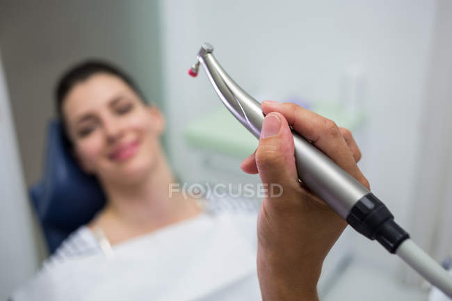 Крупный план стоматолога, держащего стоматологическую руку во время осмотра женщины в клинике — стоковое фото