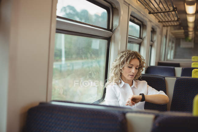 Mulher de negócios preocupada verificando o tempo enquanto viaja no trem — Fotografia de Stock
