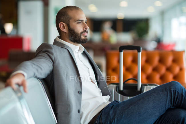 Nachdenklicher Geschäftsmann sitzt auf Stuhl im Wartebereich des Flughafenterminals — Stockfoto