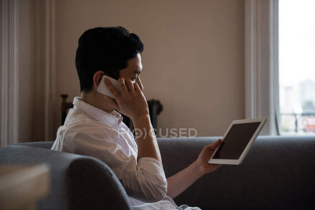 Мужчина разговаривает по мобильному телефону в гостиной дома — стоковое фото