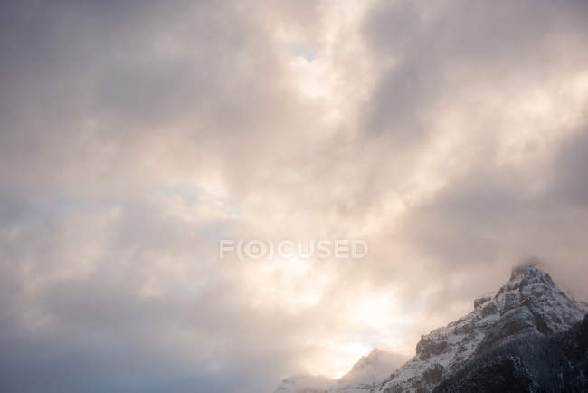 Vista panorámica de hermosas montañas cubiertas de nieve contra nublado - foto de stock