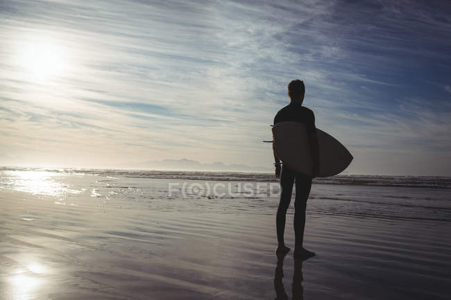 Силует серфера, що стоїть з дошкою для серфінгу на пляжі — стокове фото