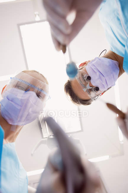 Vue à angle bas des dentistes tenant des outils dentaires à la clinique dentaire — Photo de stock