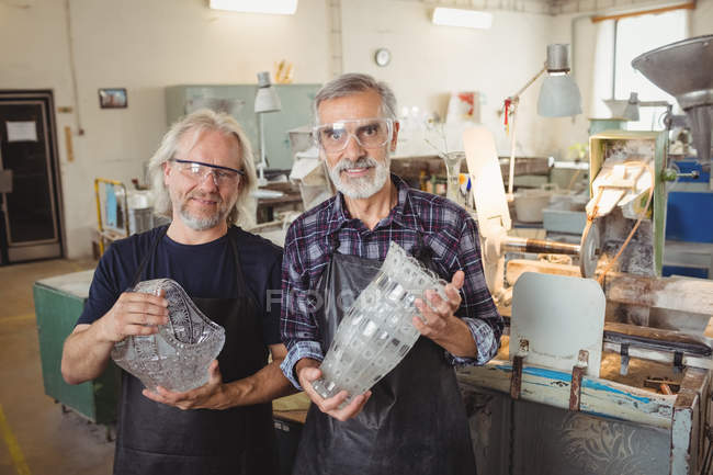 Retrato del equipo de sopladores de vidrio con brazos cruzados en fábrica de soplado de vidrio - foto de stock