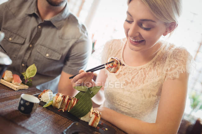 Beautiful woman having sushi in restaurant — Stock Photo