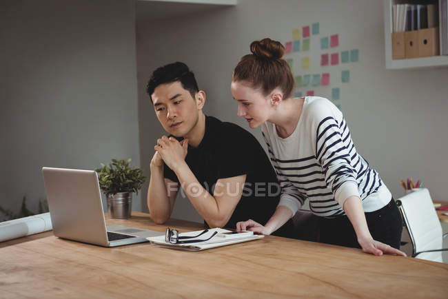 Business executives discussing over laptop in office — Stock Photo
