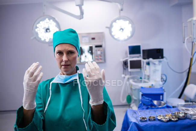 Portrait de chirurgienne portant des gants chirurgicaux dans le bloc opératoire de l'hôpital — Photo de stock