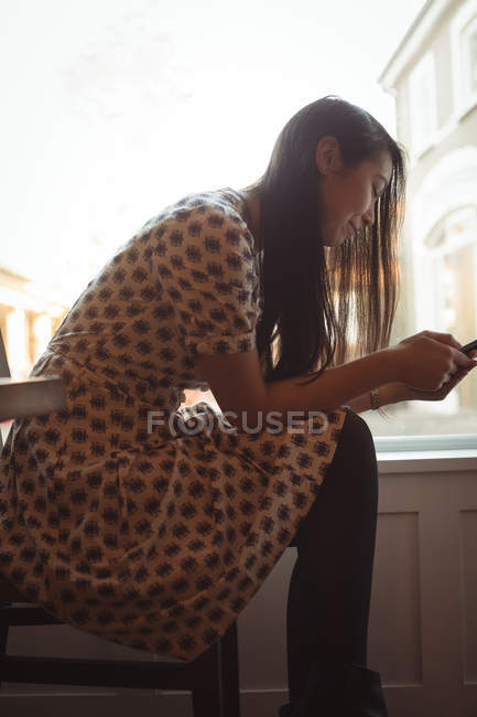 Frau benutzte Handy am Fenster eines Cafés — Stockfoto