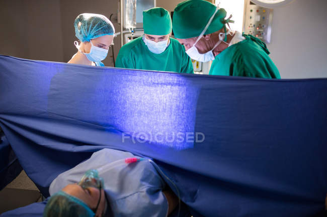Медицинская команда, осматривающая беременную женщину во время родов в операционной — стоковое фото