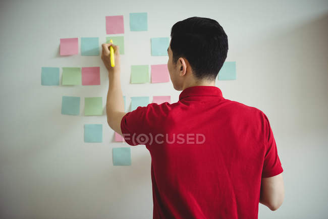 Business executive writing on sticky notes in office — Stock Photo
