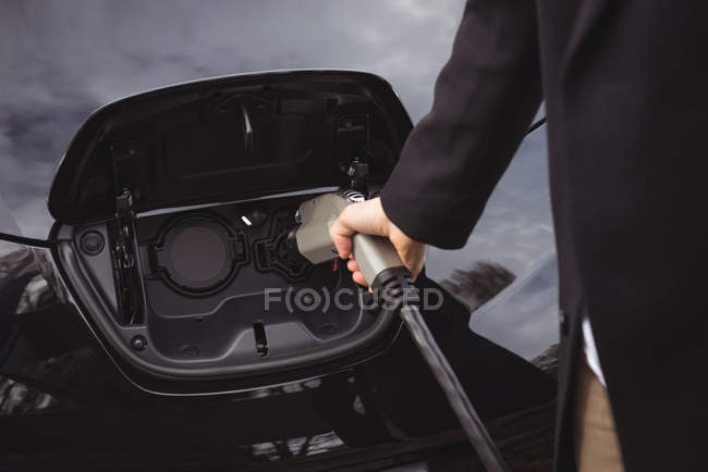 Man charging electric car at electric vehicle charging station — Stock Photo