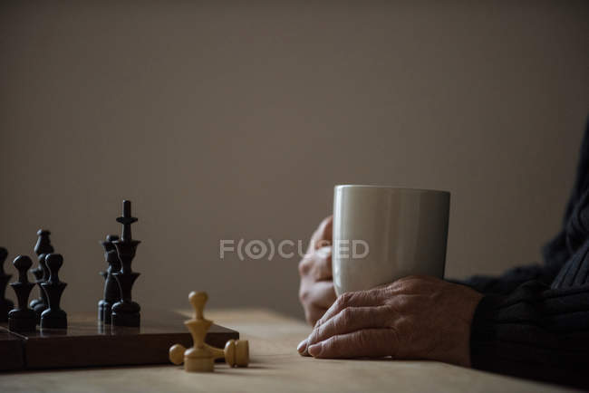 Mi-section de l'homme tenant une tasse de café à la maison — Photo de stock
