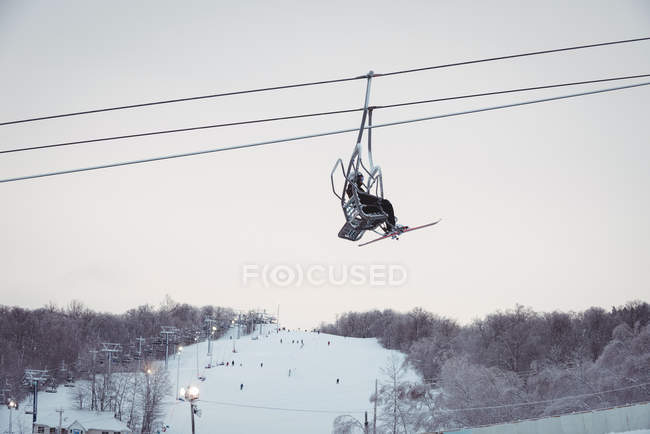 Человек на лыжном подъемнике поднимается на гору — стоковое фото