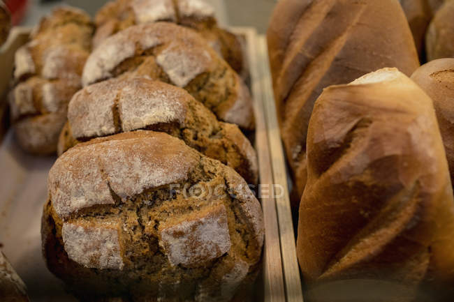 Pan Einkorn y pan de masa fermentada se mantienen juntos en el mostrador de panadería en el supermercado - foto de stock