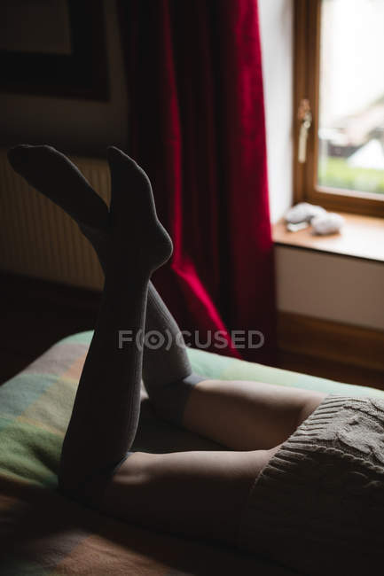 Low section of woman lying on bed in bedroom — Stock Photo