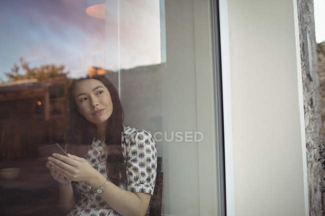 Frau benutzte Handy am Fenster eines Cafés — Stockfoto