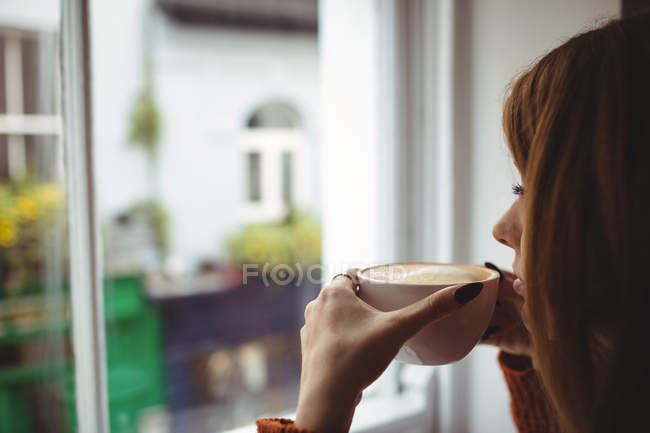 Primer plano de la mujer tomando café en la ventana del restaurante - foto de stock