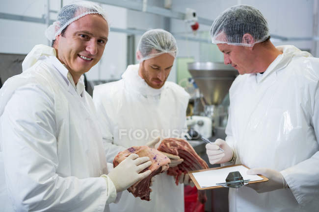 Carniceiros mantendo registros na área de transferência na fábrica de carne — Fotografia de Stock