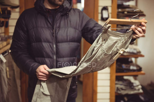 Primer plano del hombre seleccionando ropa en una tienda de ropa - foto de stock