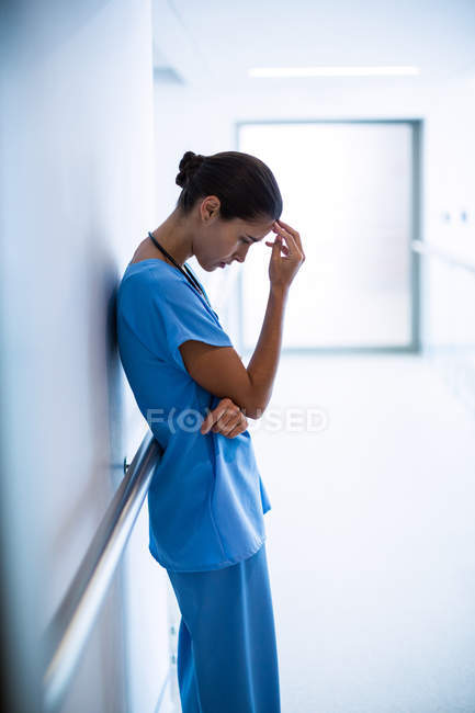 Enfermera triste parada en el pasillo en el hospital - foto de stock