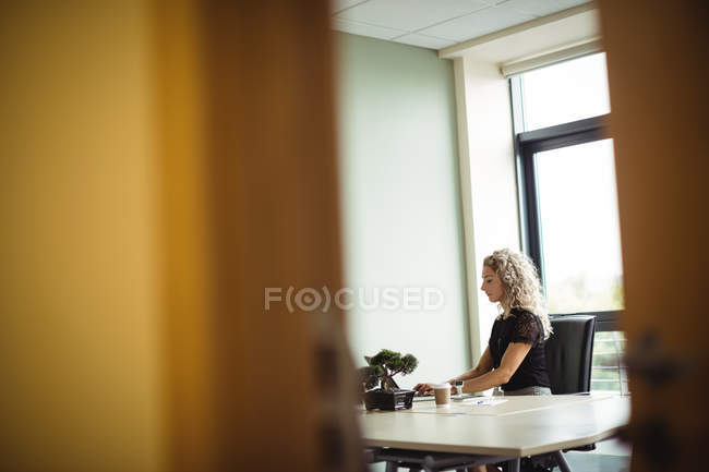 Businesswoman working on laptop in office interior — Stock Photo