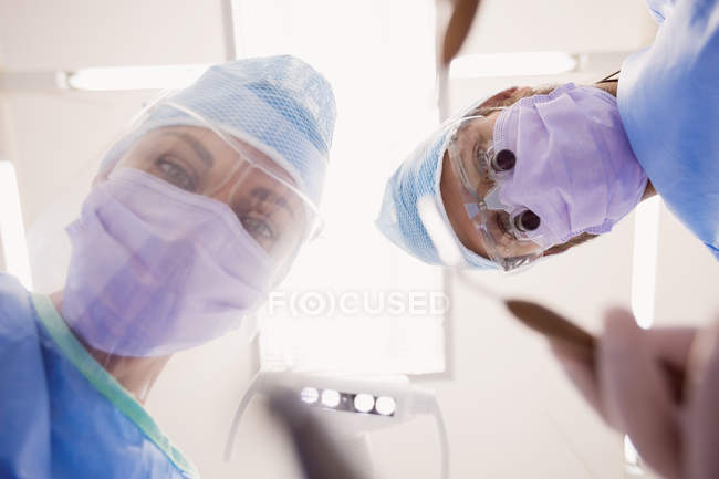 Vista de ángulo bajo de dentistas que sostienen herramientas dentales en clínica dental - foto de stock