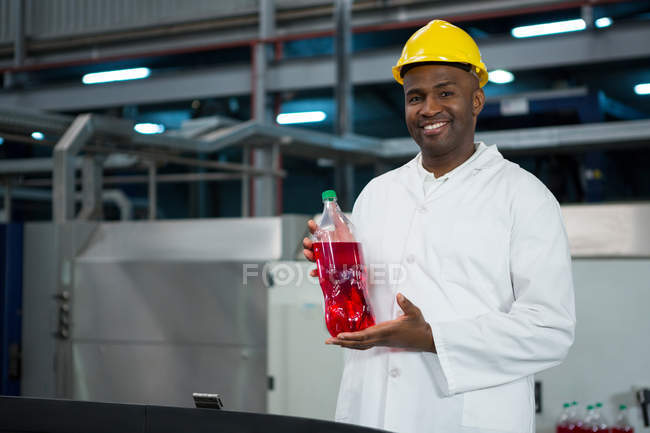 Retrato de trabalhador masculino mostrando garrafa de suco na fábrica — Fotografia de Stock