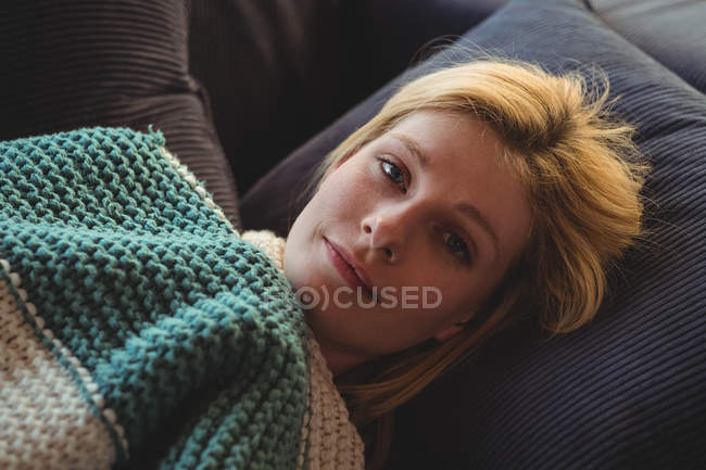 Porträt einer schönen Frau, die zu Hause auf dem Sofa im Wohnzimmer liegt — Stockfoto