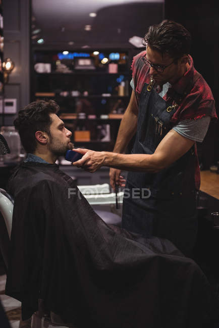 Mann bekommt Bart von Friseur mit Trimmer im Friseurladen rasiert — Stockfoto
