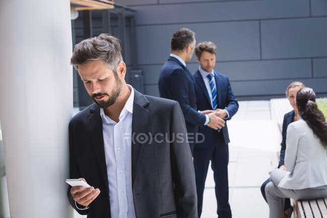 Uomo d'affari che utilizza il telefono cellulare al di fuori dell'edificio degli uffici — Foto stock