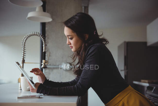 Femme utilisant la tablette numérique dans la cuisine à la maison — Photo de stock