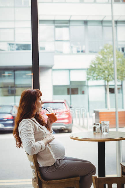 Pregnant businesswoman having fruit juice in office cafeteria — Stock Photo