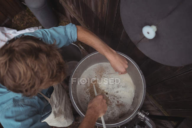 Mann testet Temperatur von Bier in Würze bei der Bierherstellung in der Hausbrauerei — Stockfoto