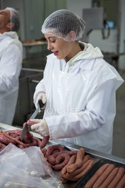 Жіночий м'ясник для різання ковбас з ножем на м'ясному заводі — стокове фото