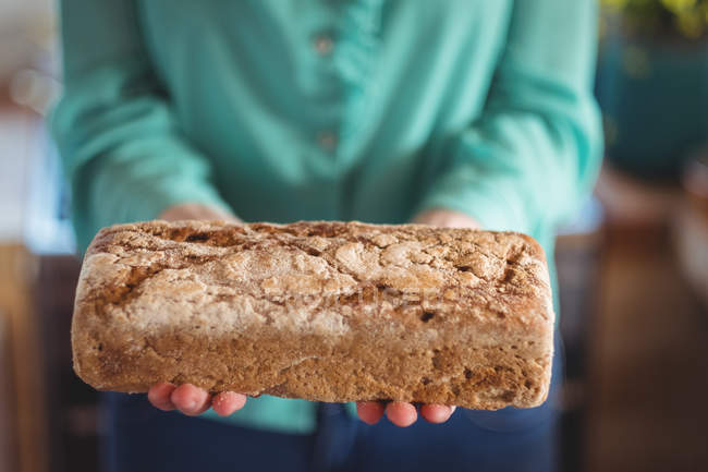 Sezione media della donna che tiene il pane al forno a casa — Foto stock