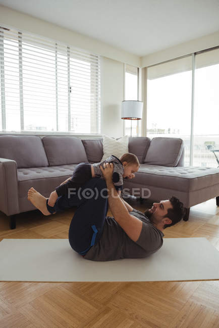 Pai brincando com seu bebê na sala de estar em casa — Fotografia de Stock