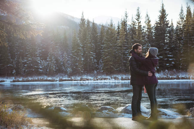 Couple romantique embrassant par la rivière en hiver — Photo de stock