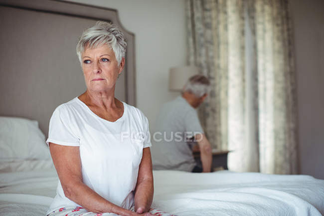 Mulher idosa preocupada e pensativa sentada no quarto de cama — Fotografia de Stock