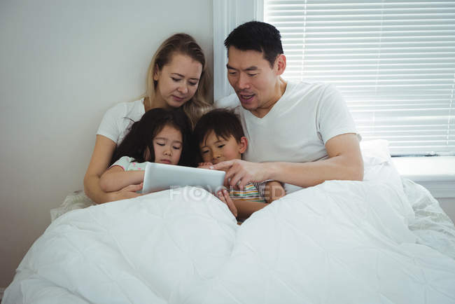 Família usando tablet digital no quarto em casa — Fotografia de Stock