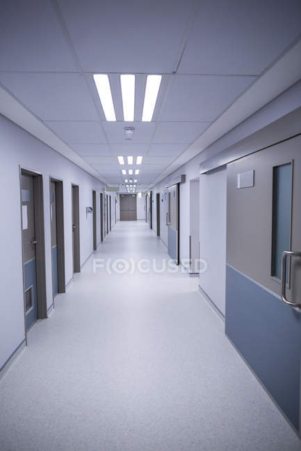 Pasillo vacío de un hospital con puertas y luces - foto de stock