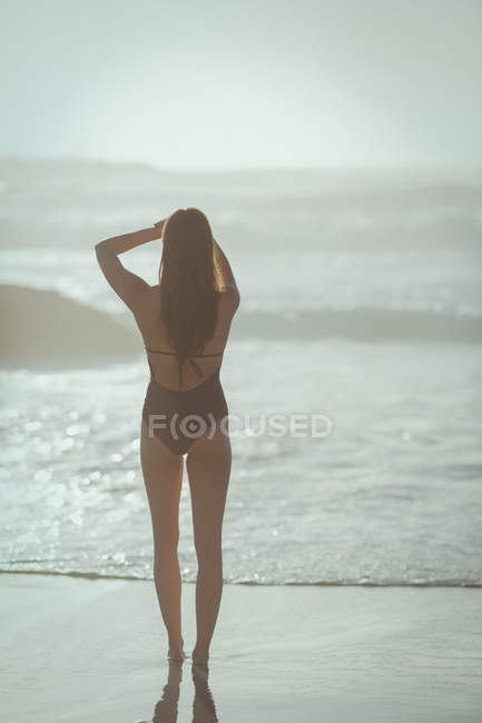 Visão traseira da mulher de pé na praia em um dia ensolarado — Fotografia de Stock