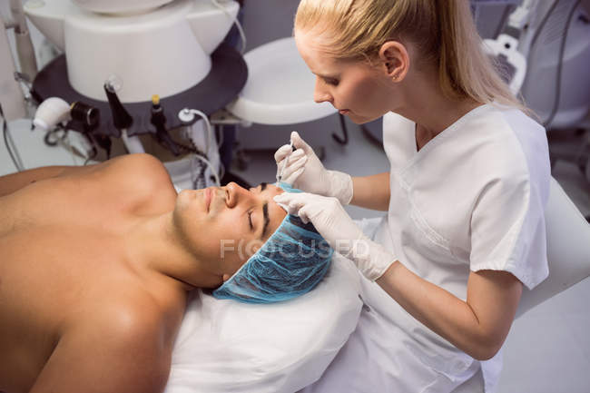 Лікар дає ін'єкції ботоксу на пацієнта чоловічої статі в клініці — стокове фото
