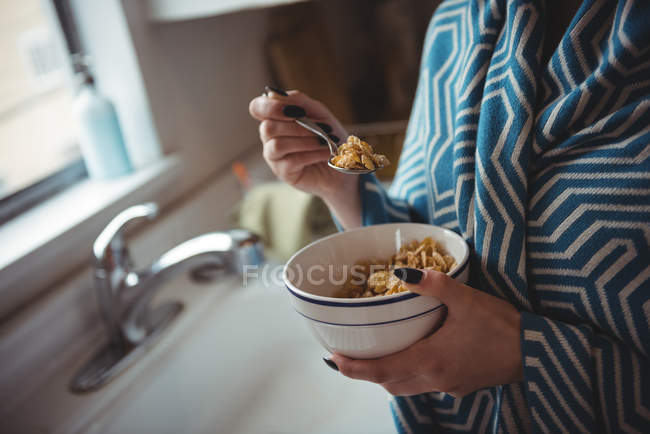 Parte média da mulher comendo cereais na cozinha em casa — Fotografia de Stock