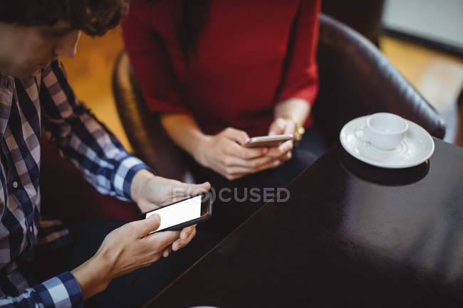 Couple using mobile phone in restaurant — Stock Photo